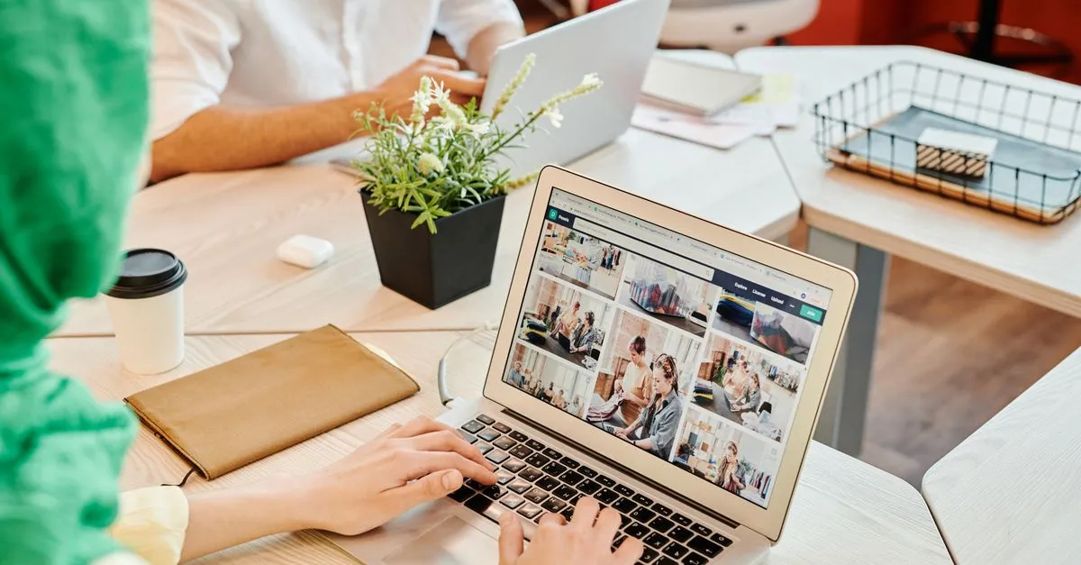 Two people working on laptops at a shared office desk